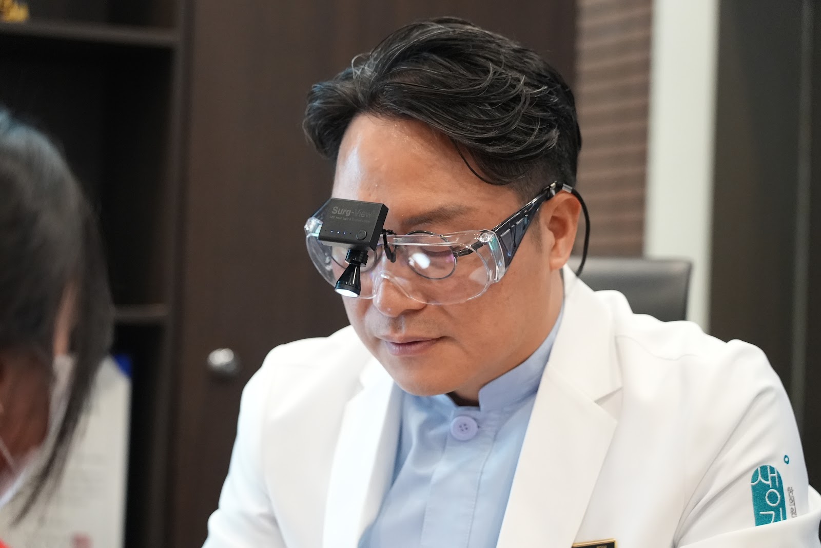 확대경을 쓰고 내원객의 피부 병변을 가까이에서 살핍니다.